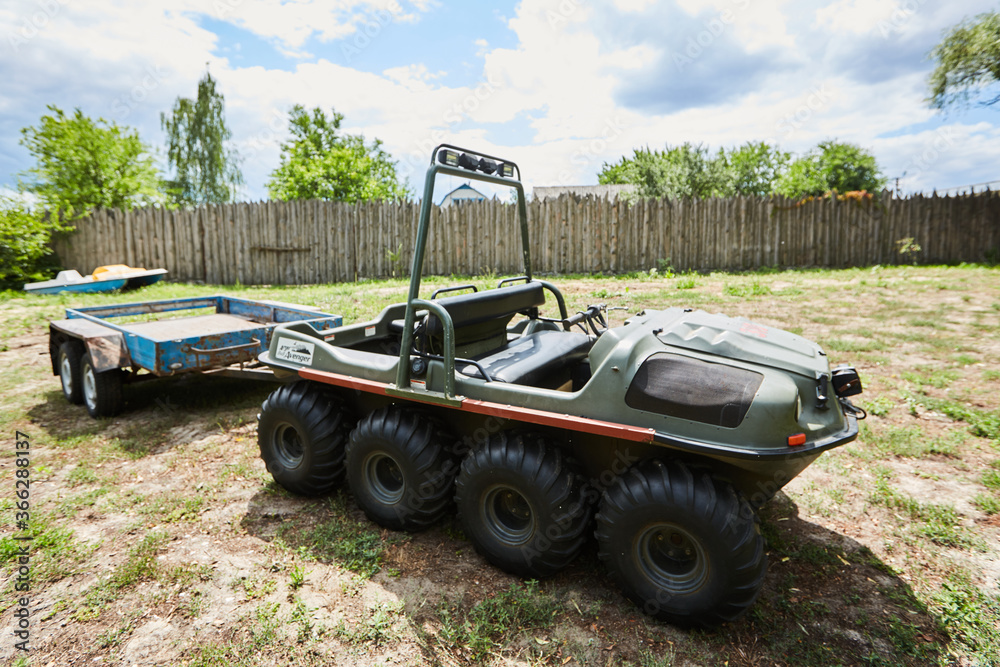 eight-wheeled all-terrain vehicle with a trailer on a meadow on a summer day