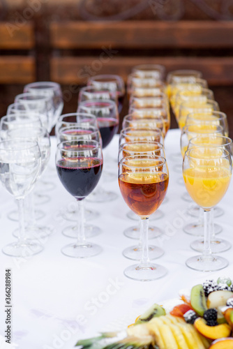 glass wine glasses filled with drinks stand in rows