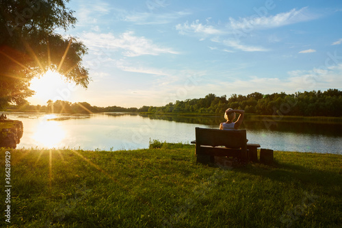 Woman Sitting On Bench During A Beautiful Sunset