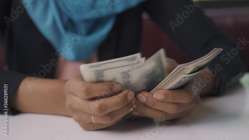 Arab woman counting dollar from work.