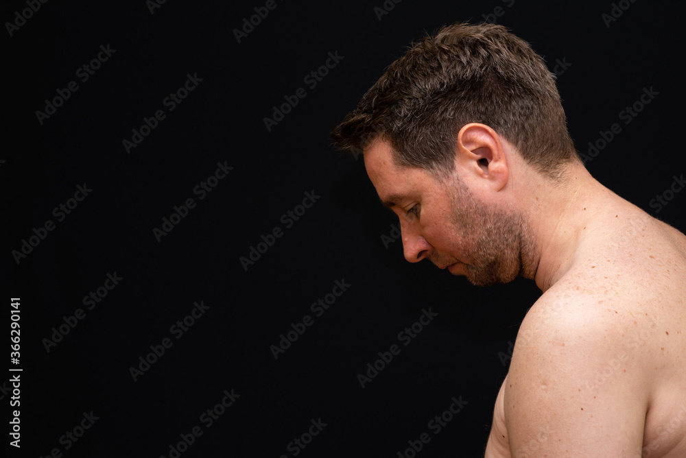 Side view thoughtful undressed middle man demonstrating reverie. Black wall Side view thoughtful undressed middle man demonstrating reverie. Black wall
