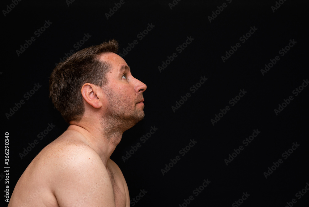 Side view thoughtful undressed middle man demonstrating reverie. Black wall Side view thoughtful undressed middle man demonstrating reverie. Black wall