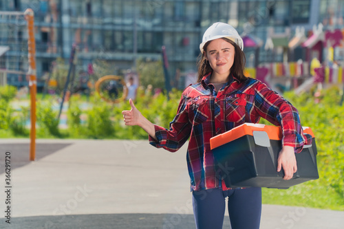Woman in construction clothes with a white helmet in a plaid shirt