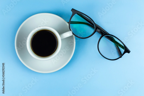 Cup of coffee, glasses. Blue background