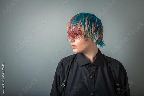 Portrait of a young woman with multi colored hair against a grey background photo