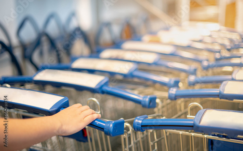 Female hand pushing the trolley cart shopping the decorate funiture for interior inside the house in the big warehouse store.