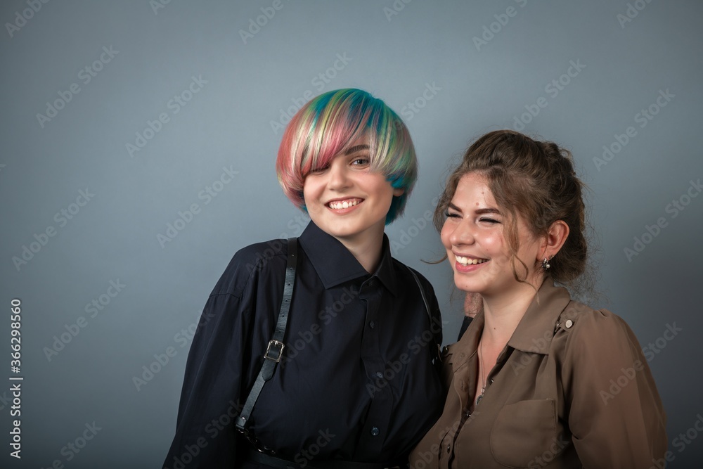 Two pretty young white girls smiling and posing on grey background people portrait with positive emotions