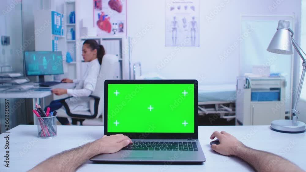 Pov shot of physician using laptop with chroma key in hospital cabinet and doctor looking at x-ray image. Medic using notebook with green screen on display in medical clinic. Pov shot of physician using laptop with chroma key in hospital cabinet and doctor looking at x-ray image. Medic using notebook with green screen on display in medical clinic.
