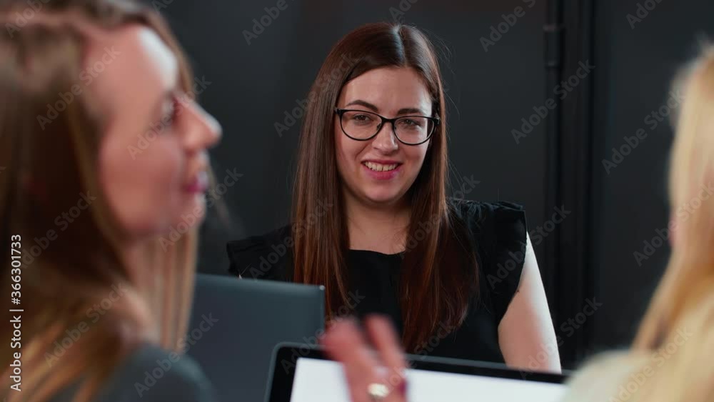 Young happy millennial Caucasian office worker woman in eyeglasses smiling at business coworking team meeting table. Young happy millennial Caucasian office worker woman in eyeglasses smiling at business coworking team meeting table.