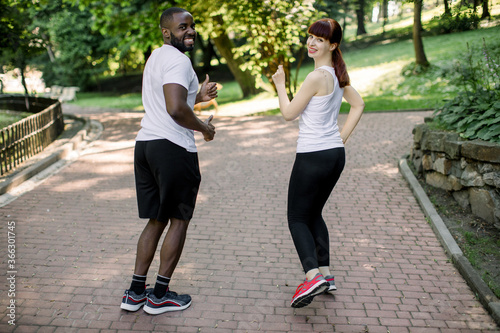Young couple, African man and Caucasian woman, getting ready for running and fitness training outdoors at the city park. Sport, exercise, fitness, workout. Healthy lifestyle.