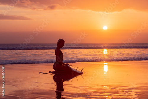 Portrait of surfer girl with beautiful body on the beach with surfboard at colourful sunset time © Lila Koan