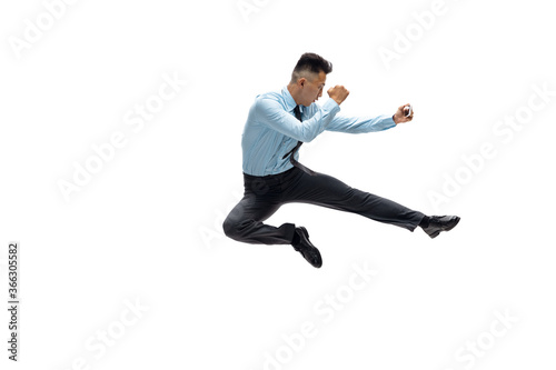 In jump. Man in office clothes practicing taekwondo on white background like professional player, sportsman. Unusual look for businessman in motion, action with ball. Sport, healthy lifestyle