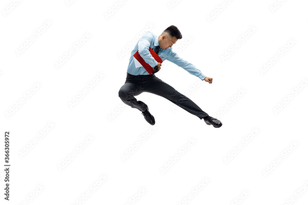 In jump. Man in office clothes practicing taekwondo on white background like professional player, sportsman. Unusual look for businessman in motion, action with ball. Sport, healthy lifestyle