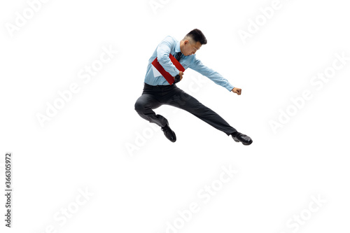 In jump. Man in office clothes practicing taekwondo on white background like professional player, sportsman. Unusual look for businessman in motion, action with ball. Sport, healthy lifestyle © master1305