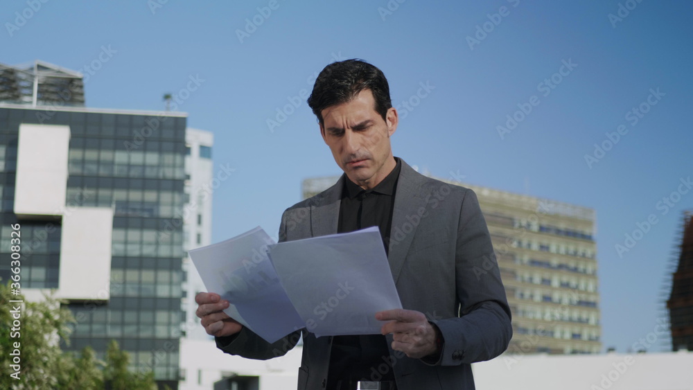 Businessman reading documents on street. Male manager looking business papers