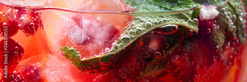 summer cocktail with mint leaf, lemon slices and red berries with pomegranate and ice cubes,