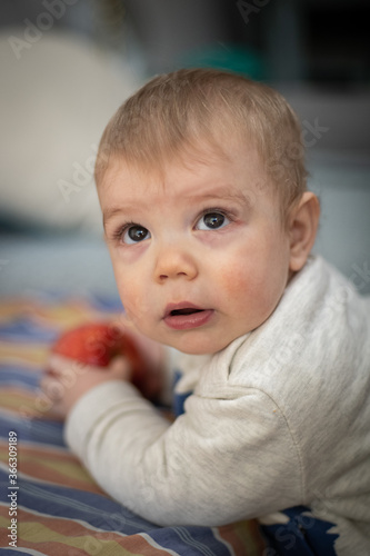 Bebé jugando y comiendo una manzana mirando hacia la cámara