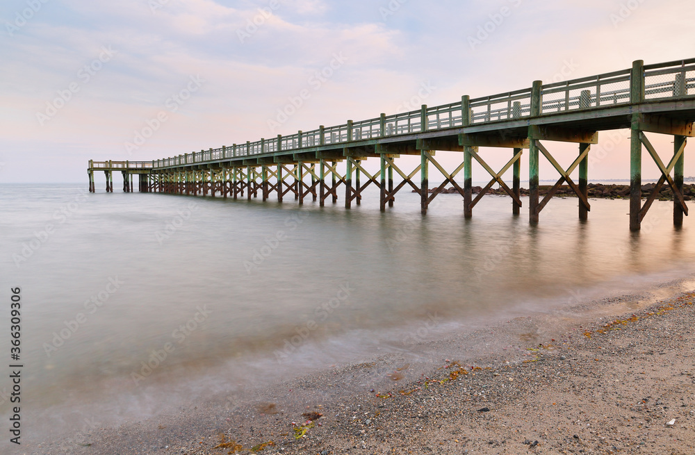 Overview of beautiful fishing pier after sunset at low tide at Walnut Beach, Milford Connecticut, USA.