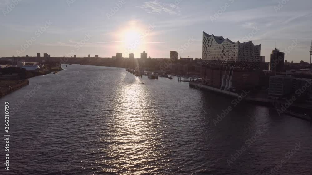 Pan around aerial view of rippling river and modern city Hamburg with Elbphilharmonie in foreground against cloudy sundown sky Pan around aerial view of rippling river and modern city Hamburg with Elbphilharmonie in foreground against cloudy sundown sky