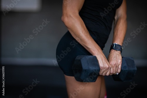 Sport woman holding a dumbbell and training for her buttock. Copy space.