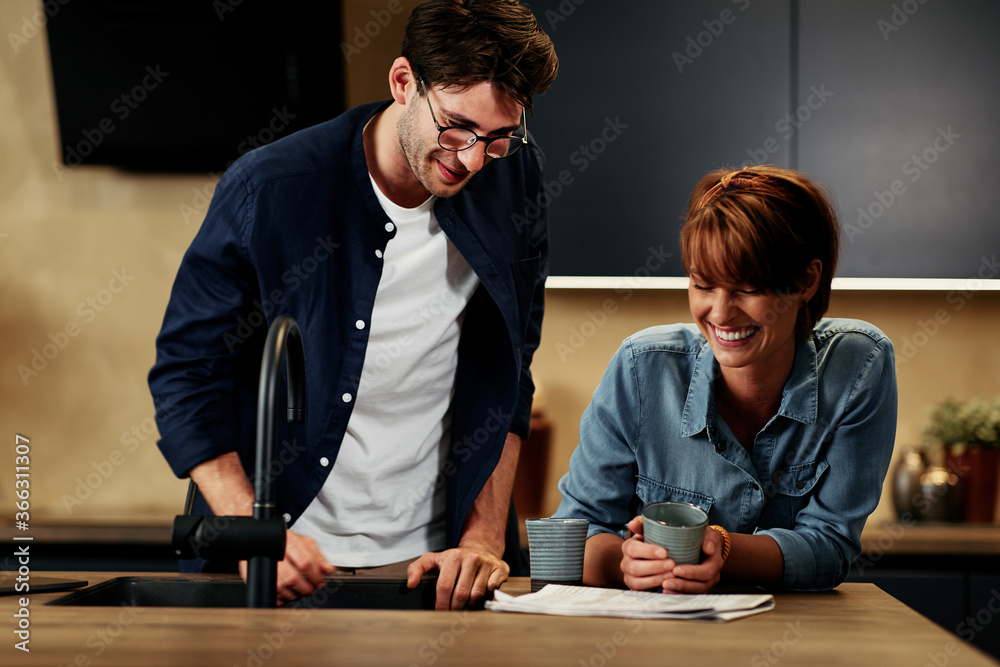 Couple laughing in their kitchen - obrazy, fototapety, plakaty 