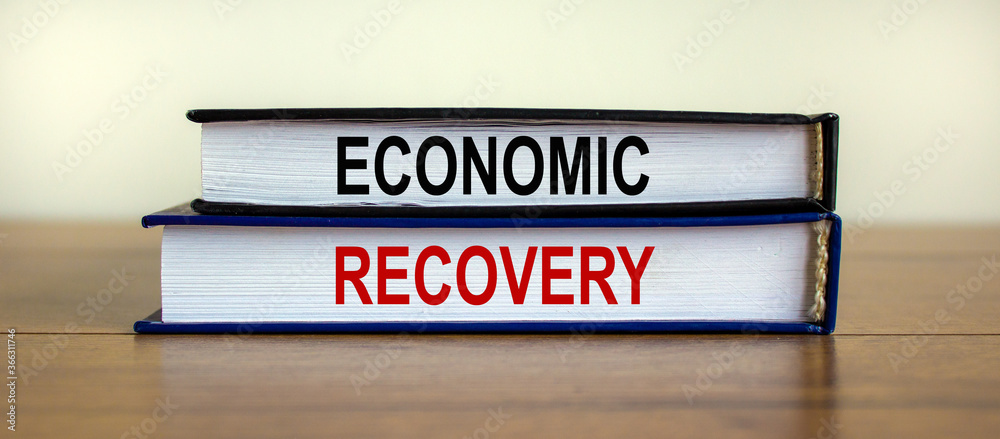 Books with text 'economic recovery' on wooden table. Beautiful white background. Business concept, copy space.