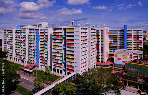 Wide angle, panoramic view of typical colourful public housing (HDB flats) in Singapore heartland on a bright sunny day with cloudy blue sky; architecture shot.