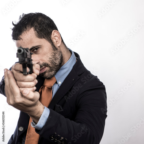 manager vestito in abito con una cravatta arancione punta una pistola e mira pro Fototapet