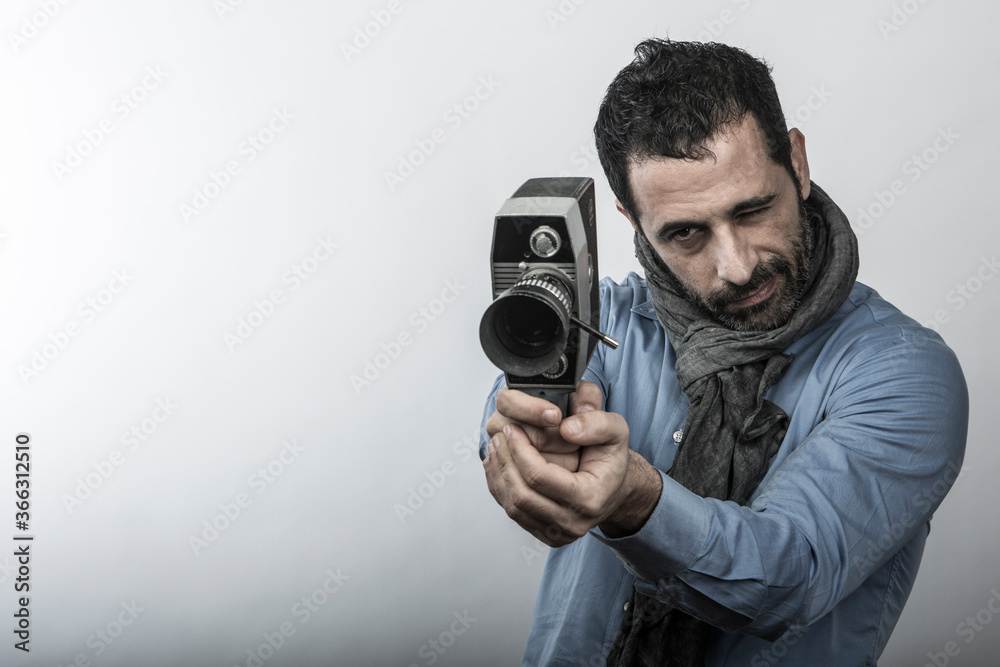 uomo in camicia blu e sciarpa utilizza una vecchia cinepresa da super 8, isolato su sfondo bianco uomo in camicia blu e sciarpa utilizza una vecchia cinepresa da super 8, isolato su sfondo bianco