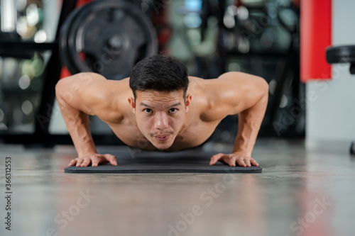 Sport man training doing push-ups exercise in fitness gym