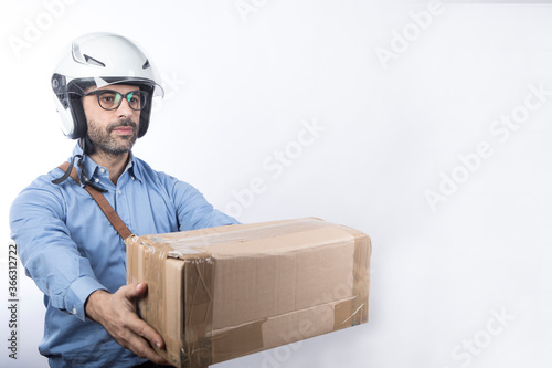 Corriere express con camicia blu, borsa a tracolla e casco da moto  si appresta a consegnare un pacco , isolato su sfondo bianco photo