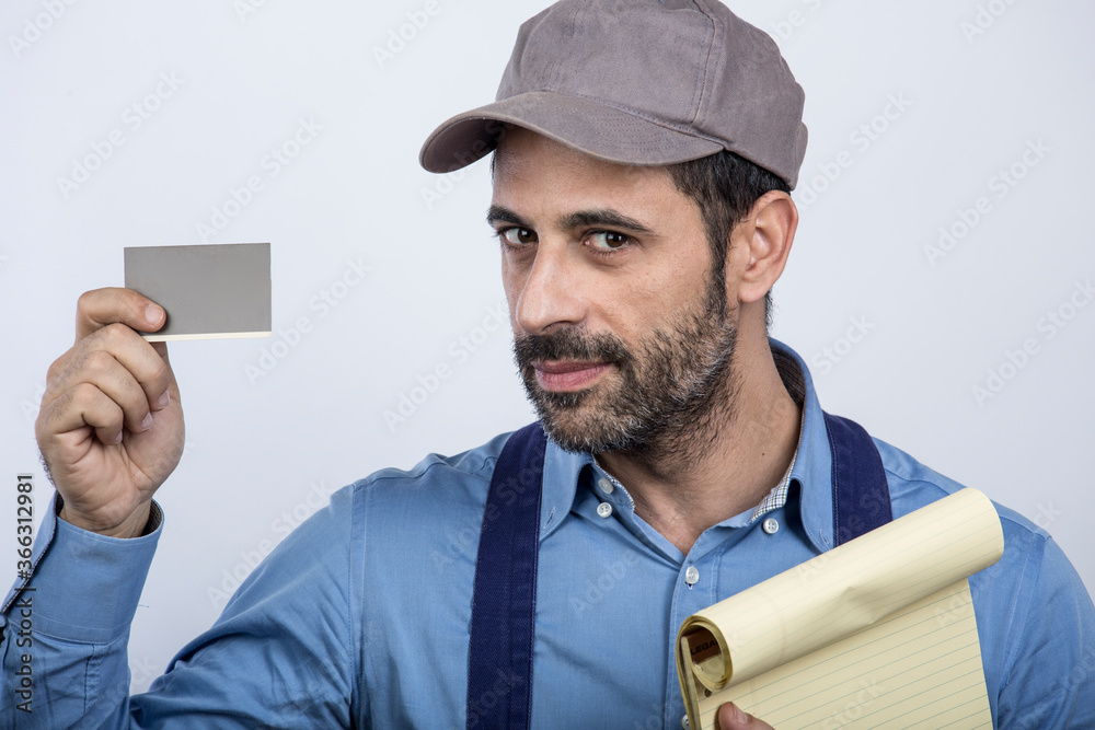 fattorino con cappellino camicia e blocco notes giallo in mano , mostra una tessera con l'altra mano, isolato su sfondo bianco fattorino con cappellino camicia e blocco notes giallo in mano , mostra una tessera con l'altra mano, isolato su sfondo bianco