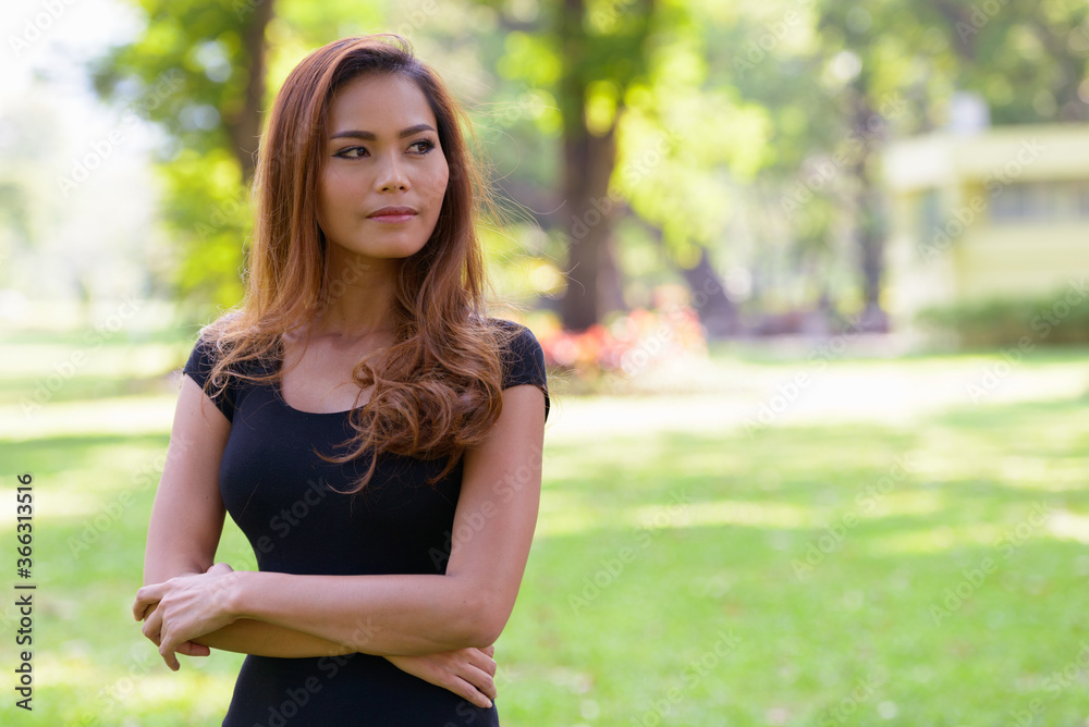 Young beautiful Asian woman thinking with arms crossed at the park outdoors Young beautiful Asian woman thinking with arms crossed at the park outdoors