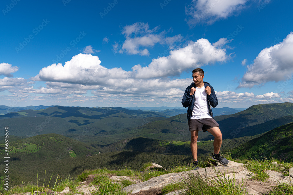 Excited man hiking on a mountain top with backpack enjoy the view and looking for adventures
