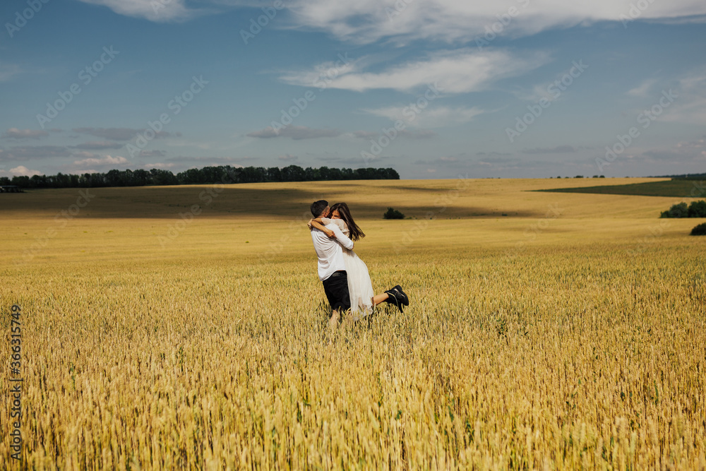 Romantic pretty young couple have fun outdoor. Happy beautiful loving couple spinning at wheat field. Happy relationship. Beautiful boy and girl feeling love and enjoy spending time with each other.