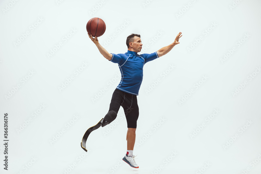 Athlete with disabilities or amputee on white studio background. Professional male basketball player with leg prosthesis training in studio. Disabled sport and healthy lifestyle concept. Achievements. Athlete with disabilities or amputee on white studio background. Professional male basketball player with leg prosthesis training in studio. Disabled sport and healthy lifestyle concept. Achievements.