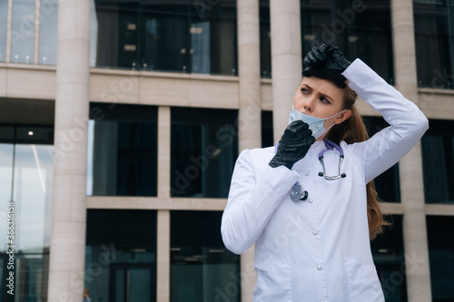 Tired girl doctor takes off medical mask. The concept of doctor after a major operation photo