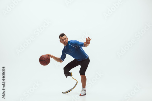 Athlete with disabilities or amputee on white studio background. Professional male basketball player with leg prosthesis training in studio. Disabled sport and healthy lifestyle concept. Achievements. © master1305