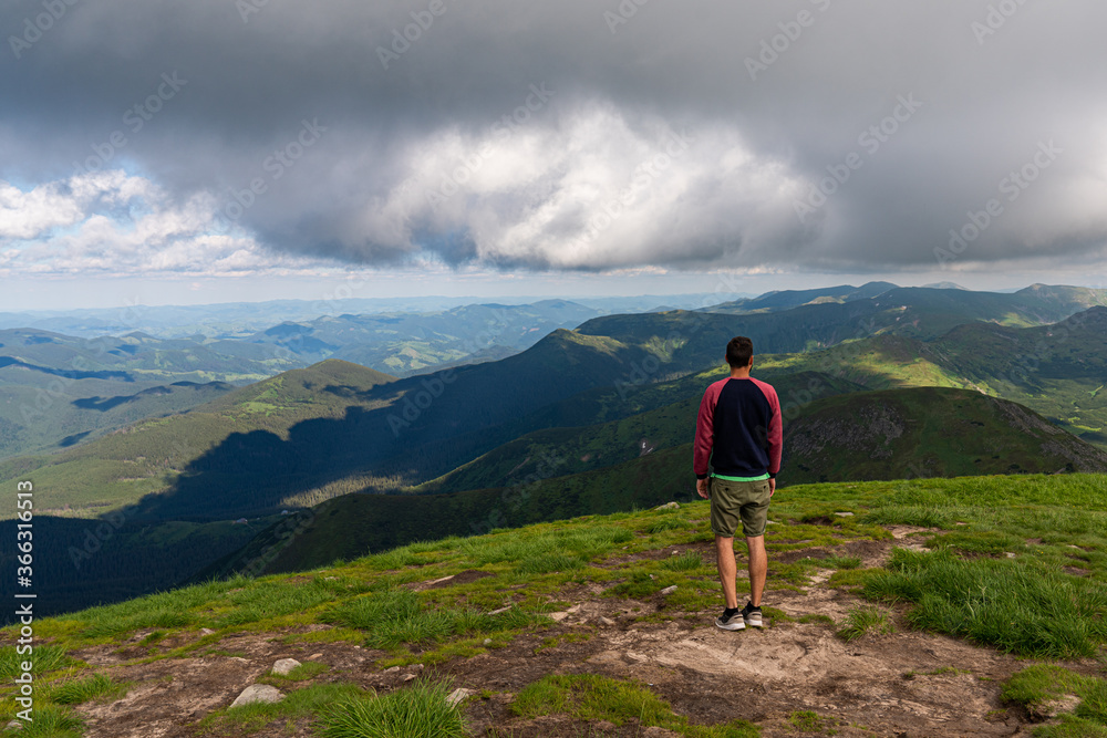 Traveler standing on high mountain cliff, enjoying scenery on mountain top. Pov view. Hiking freedom concept