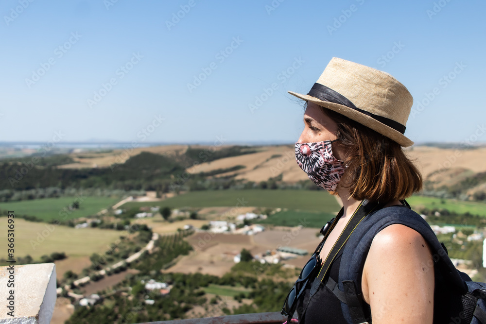Attractive young female visiting an old town while wearing a facemask during coronavirus pandemic