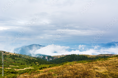 Valley with low clouds on Dragobrat. Landscape  foggy hills  forest in autumn. Daylight. Sun in the sky. Blue and blue colors. Resort in the forest.