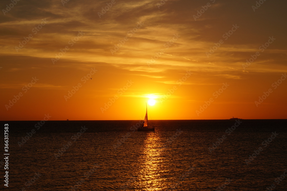 Warm summer sunset in Colonia del Sacramento, Ururguay, a sailboat can be see in the horizon Warm summer sunset in Colonia del Sacramento, Ururguay, a sailboat can be see in the horizon