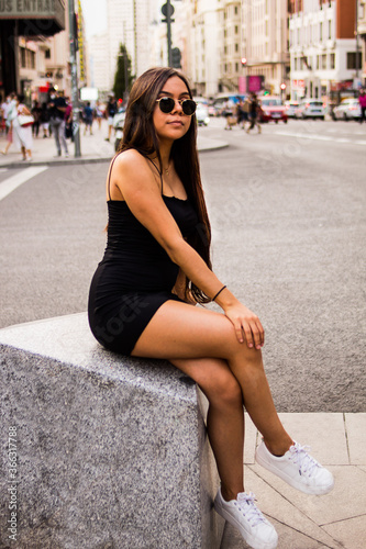 Young hispanic woman posing on a summer day while strolling through a square