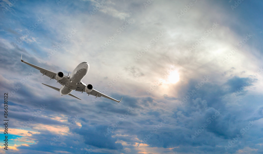 Fototapeta White passenger airplane in the sunset clouds - Travel by air transport