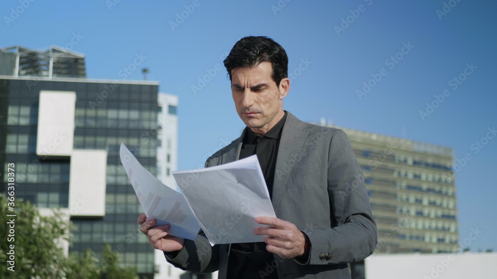Businessman working with papers on street. Entrepreneur reading documents Businessman working with papers on street. Entrepreneur reading documents