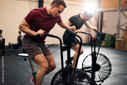 Young men exercising on stationary bikes at the gym
