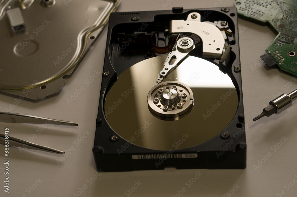 Disassembled computer hard drive on the table next to the instrumen Disassembled computer hard drive on the table next to the instrumen