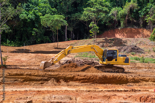 Heavy machinery. Yellow excavator placed among the excavated soil under the rays of the sun