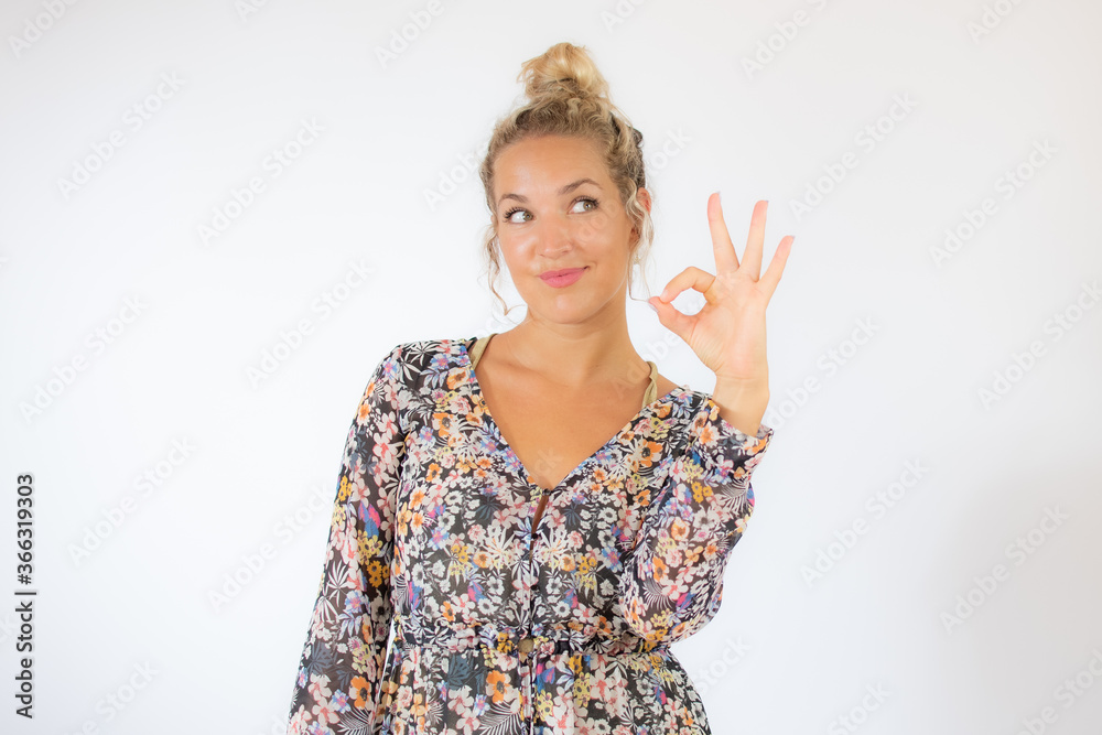 Pretty blonde woman in a flowery dress gesturing on white background Pretty blonde woman in a flowery dress gesturing on white background
