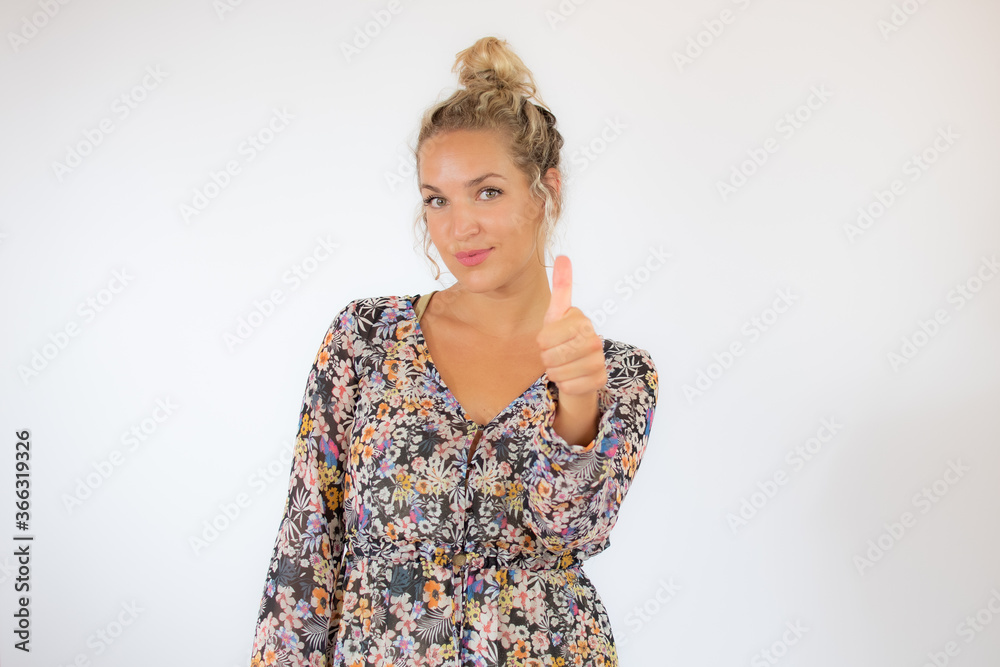Pretty blonde woman in a flowery dress gesturing on white background Pretty blonde woman in a flowery dress gesturing on white background